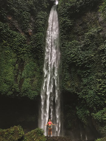 Woman Standing In Front Of Waterfalls