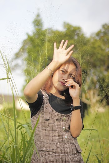 Woman Standing in Grass Field Covering Her Face from Sunray