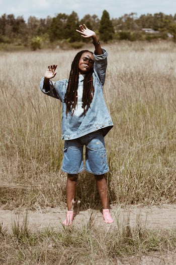 Woman Standing in Grass Field While Raising Her Hands