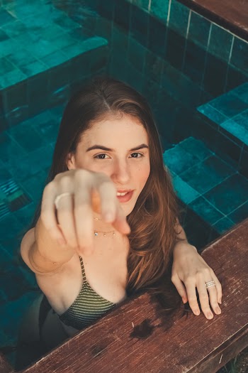 Woman Standing in Pool Reaching With Her Right Hand