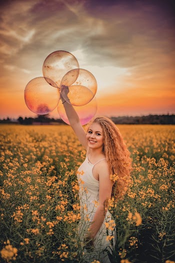 Woman Standing in Yellow Flower Field Holding Balloons