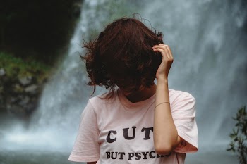 Woman Standing Looking Down While Holding Hair Near Waterfall