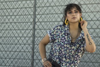 Woman Standing Near a Chain Link Fence While  Holding Her Earring