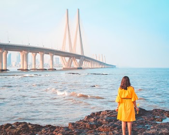 Woman Standing Near Body of Water and Bridge