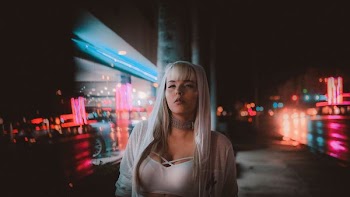 woman standing near building beside road at nighttime