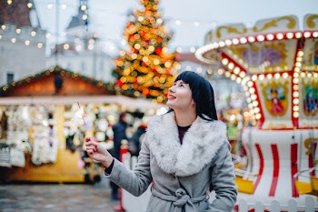 Woman Standing Near Carnival Rides and Christmas Tree