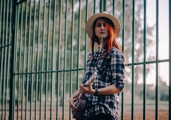 Woman Standing Near Green Fence While Playing Guitar