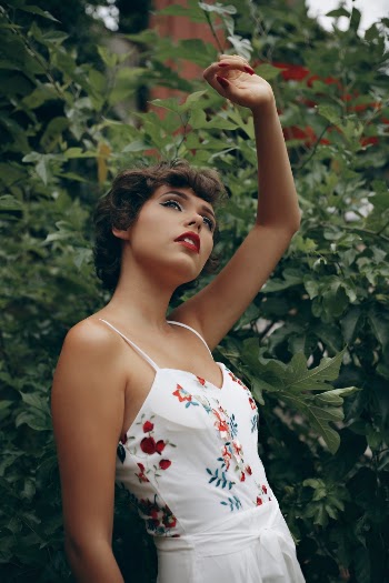 Woman Standing Near Plant While Raising Left Hand Above Head
