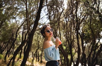woman standing near tree whike drinking