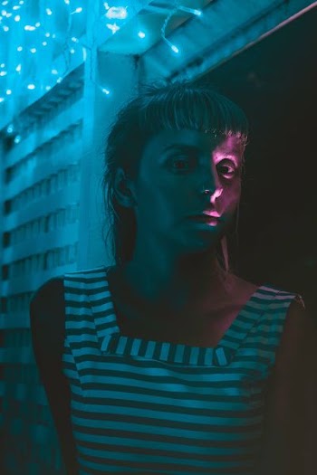 woman standing near wall with white string lights
