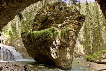 Woman Standing Near Waterfalls and Huge Rock Formation