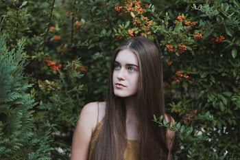 woman standing next to red flower