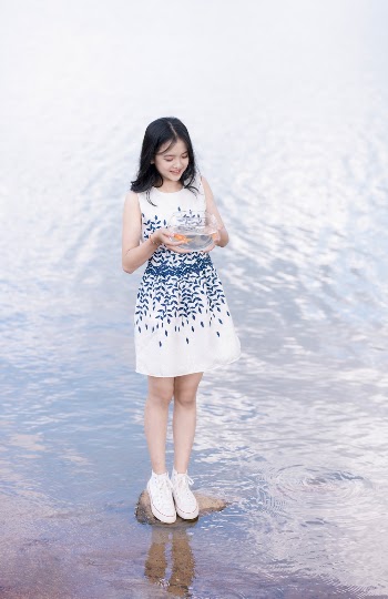 Woman Standing On A Stone Surrounded By Water