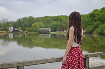 Woman Standing on Bridge and Facing Body of Water