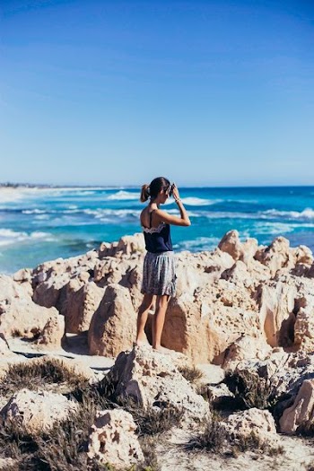 woman standing on cliff with ocean view