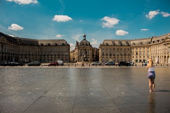 Woman Standing on Concrete Pavement in Front of Brown Concrete Buildings