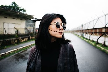 woman standing on concrete road facing to the left during daytime