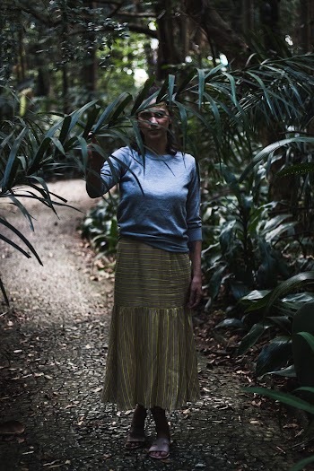Woman Standing on Dirt Road While Holding Green Leaves
