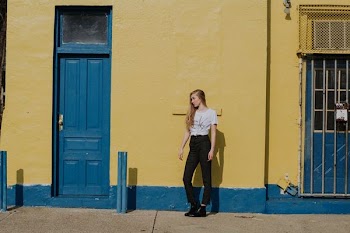 woman standing on front of yellow painted wall between two doors