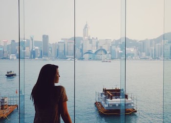 woman standing on glass window facing body of water
