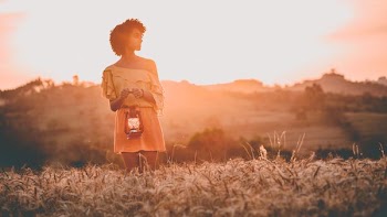 woman standing on grass field at sunset