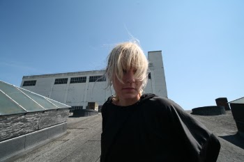 Woman Standing on Grey Concrete Pavement Under Blue Sky