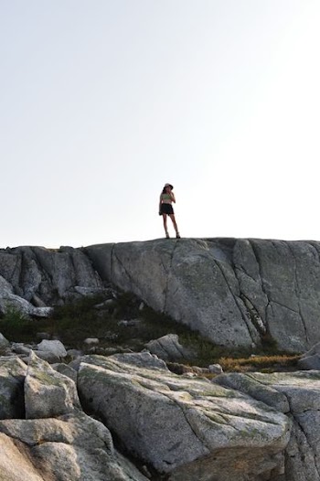 woman standing on grey rock on mountain
