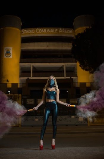 woman standing on pavement holding smoke bombs during night time
