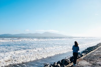 Woman Standing on Rock Near Body of Water