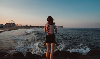 Woman Standing on Rocks Near Sea