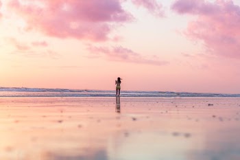 woman standing on seashore in front of body of water