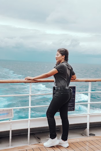 Woman Standing on Ship Overlooking Body of Water