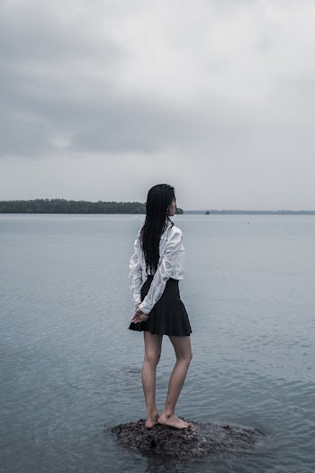 Woman Standing on Stone on Body of Water