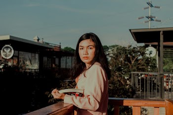 Woman Standing on Terrace Holding Book
