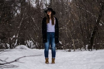 woman standing on top of snow covered ground surrounded by bare trees