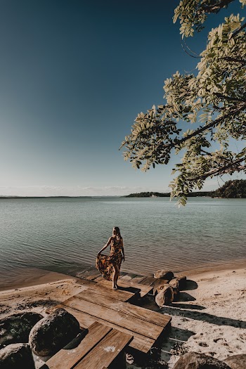 Woman Standing on Wooden Dock Viewing Body of Water and Mountain