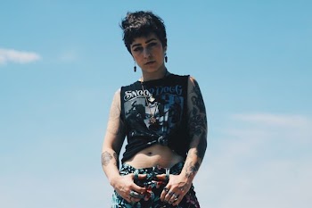woman standing wearing crop top under blue sky