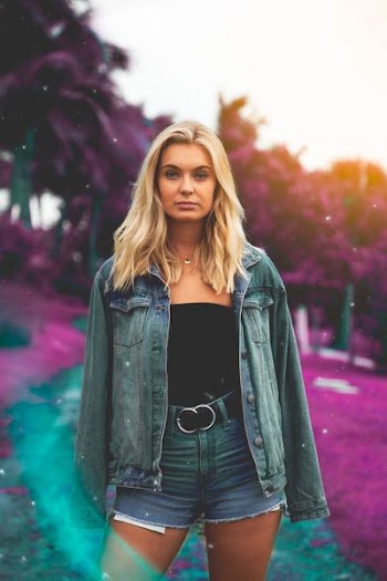 woman standing wearing denim jacket and short shorts