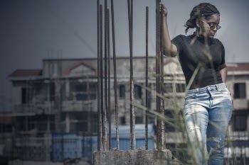 Woman Standing While Holding Corroded Brown Bar Outdoors