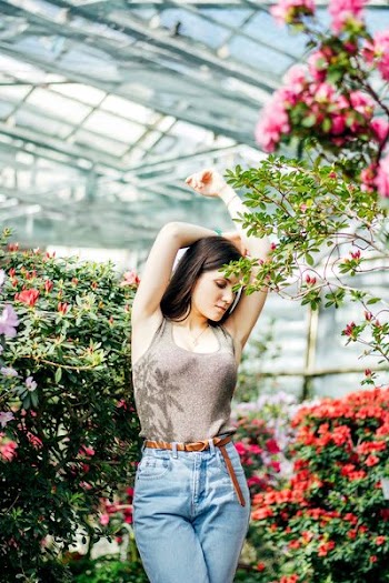 woman standing with arms raised surrounded by flowers