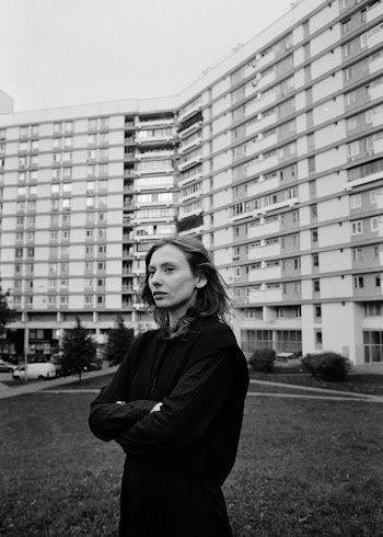 Woman Standing with Folded Hands Before Huge Residential Building · Free Stock Photo