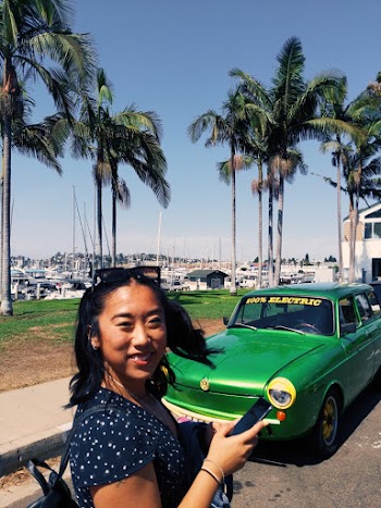 Woman Stands and Smiles Near Green Car