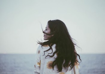 woman stands in front of calm water at daytime