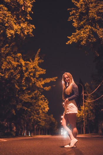 Woman Stands in Street Surrounded By Trees