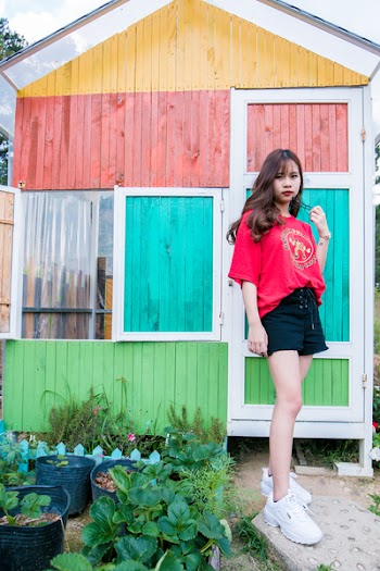 Woman Stands Near Multicolored Wooden House