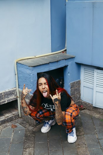 Woman Sticking Tongue Squatting On Pavement