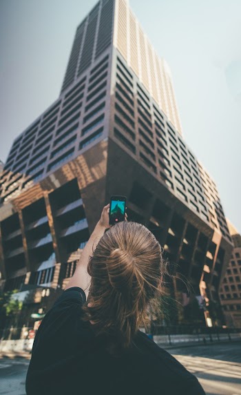 Woman Taking a Picture of a High-rise Building during Day