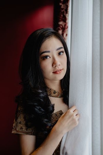 woman taking photo behind gray curtain
