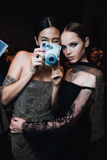 woman taking photo beside another woman using instant c