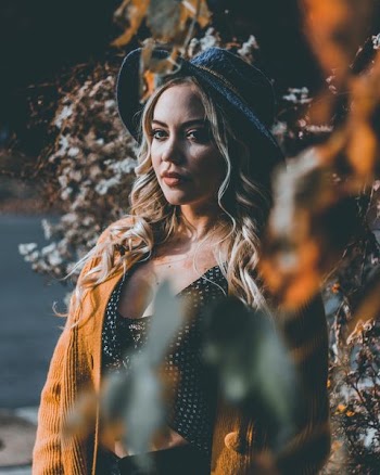 woman taking photo beside tree at daytime